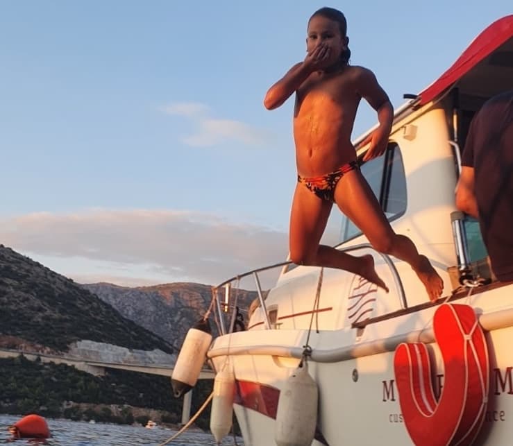 Boy jumping off the boat into the sea